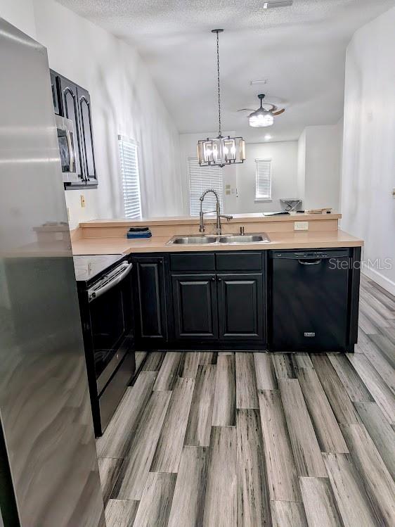 A kitchen features black cabinets, stainless steel appliances, and wood-look tile flooring — 1021 LOVE LANE UNIT 39, APOPKA, FL