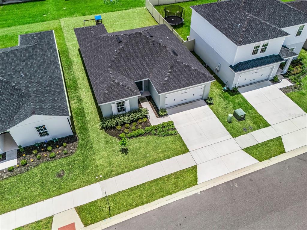 An aerial view shows a single-story house with a dark roof, driveway, and landscaped yard — 1565 TEXAS AVENUE, SUMTERVILLE, FL