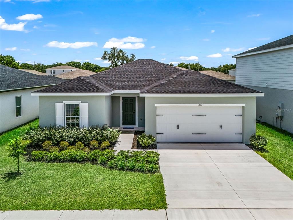 A single-story house with a gray exterior, a two-car garage, and a landscaped front yard — 1565 TEXAS AVENUE, SUMTERVILLE, FL
