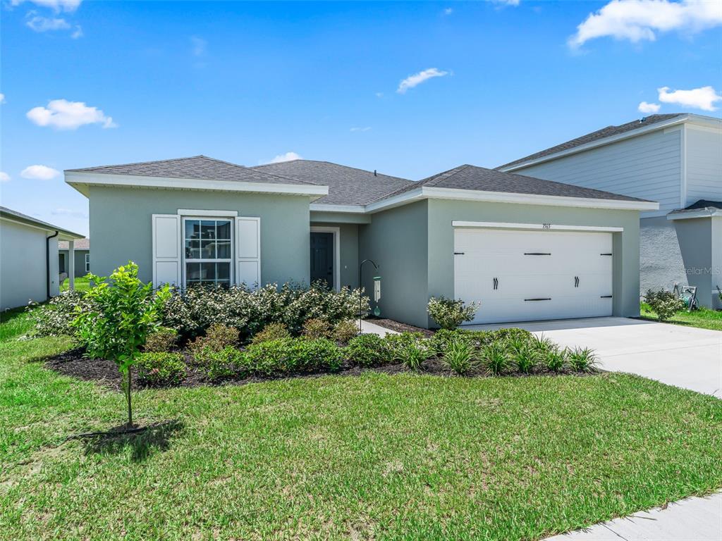 A single-story house with a light green exterior, white garage door, and a front lawn — 1565 TEXAS AVENUE, SUMTERVILLE, FL