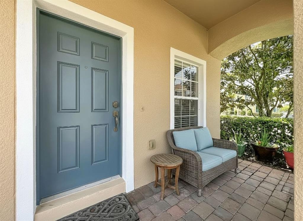 A blue front door and a wicker loveseat sit on a paved front porch — 16543 CEDAR CREST DRIVE, ORLANDO, FL