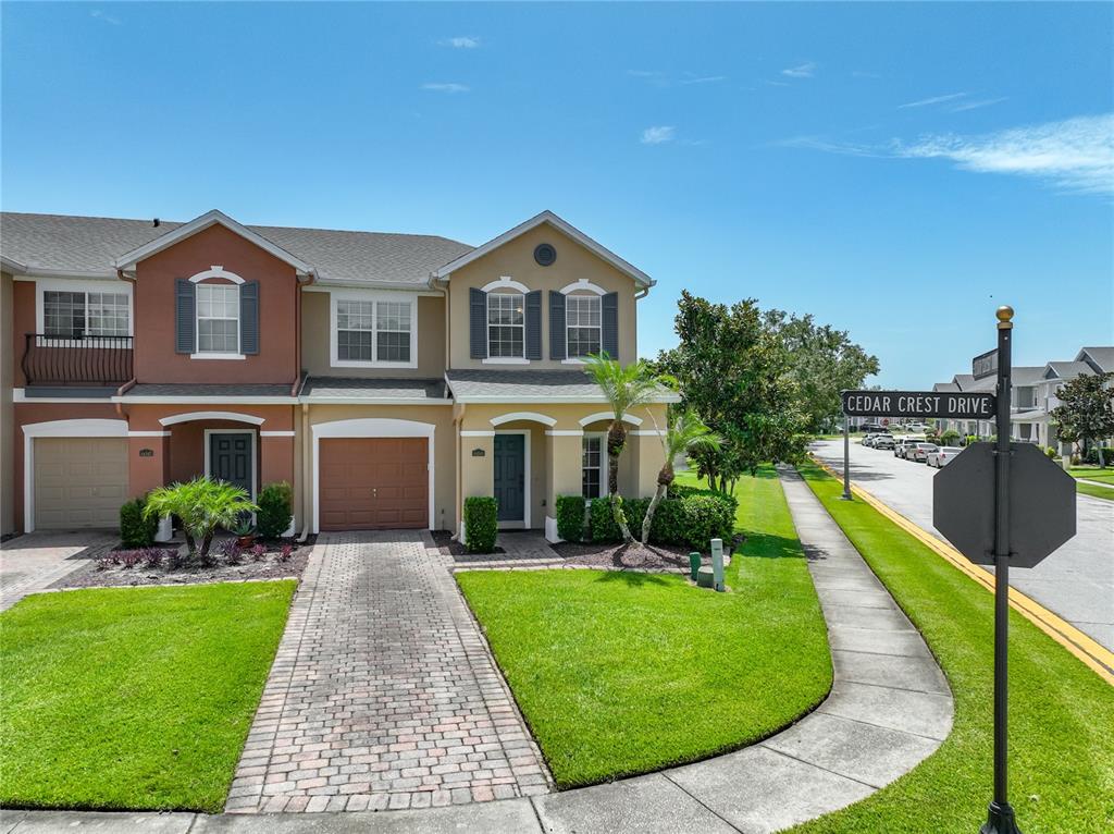 A two-story townhouse with a brick driveway, tan and brown siding, and a grassy lawn — 16543 CEDAR CREST DRIVE, ORLANDO, FL