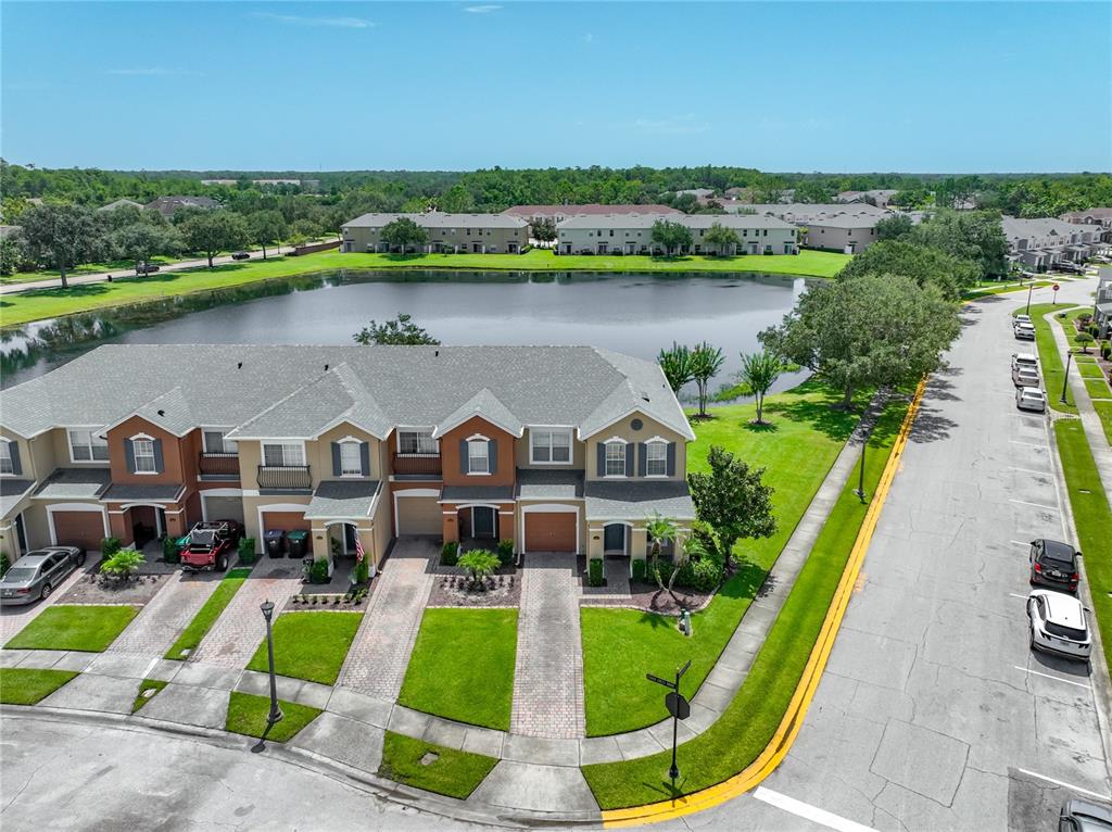An aerial view shows a multi-unit townhouse complex with a pond and street parking — 16543 CEDAR CREST DRIVE, ORLANDO, FL