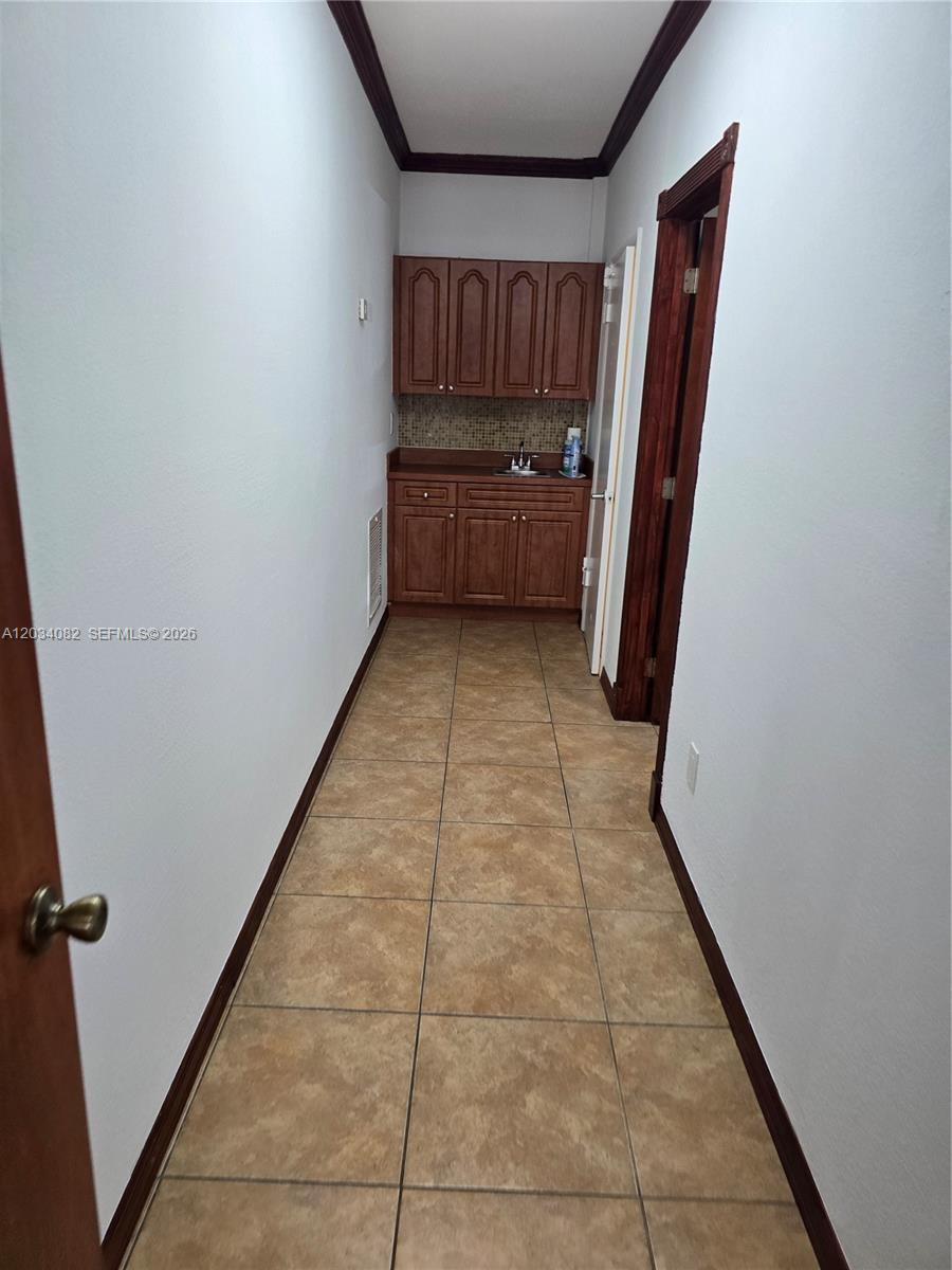 A narrow hallway features a small wet bar with wooden cabinets and tiled flooring — 1745 W 37th St # 17, Hialeah FL 33012, HIALEAH, FL