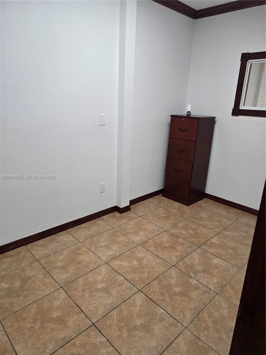 A small room features light-colored walls, dark wood trim, and tan tile flooring — 1745 W 37th St # 17, Hialeah FL 33012, HIALEAH, FL