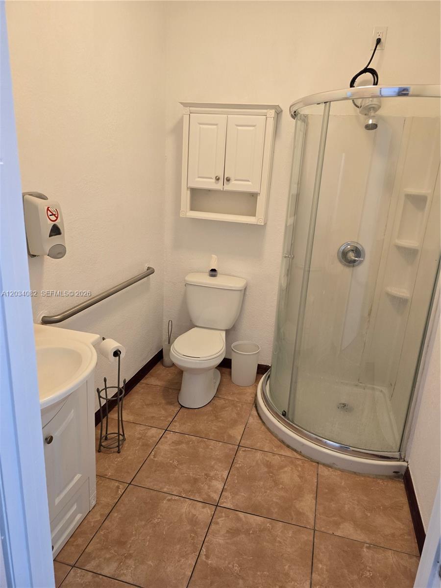 A bathroom features a corner shower, a white toilet, a vanity, and tan floor tiles — 1745 W 37th St # 17, Hialeah FL 33012, HIALEAH, FL