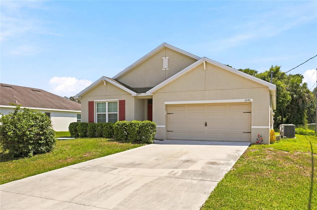 A single-story house with a beige stucco exterior, a two-car garage, and red shutters — 2096 SW LEAFY ROAD, PORT ST LUCIE, FL