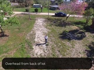 An aerial view of a vacant, grassy residential lot with a person standing in the center — 9320 CANAL ROAD, HAINES CITY, FL
