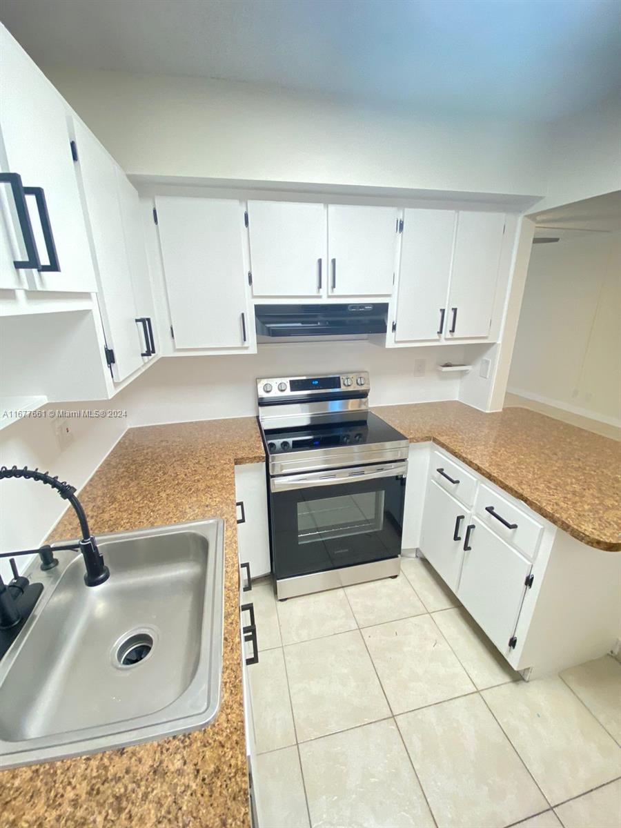 A kitchen features white cabinets, a stainless steel stove, and speckled brown countertops — 2029 NW 46th Ave # E308, Lauderhill FL 33313, LAUDERHILL, FL