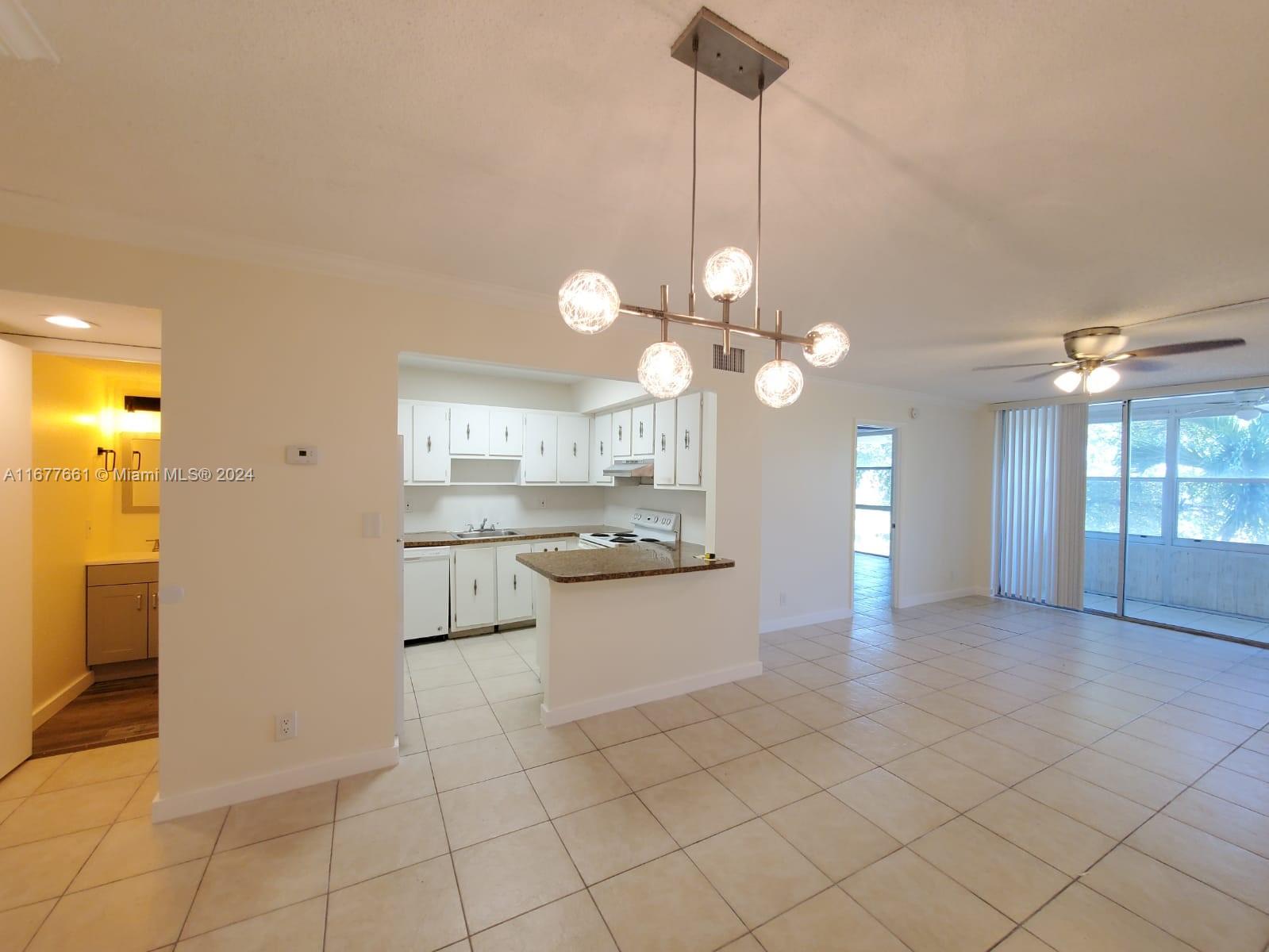 An open-concept dining and living area features tile flooring, a modern chandelier, and a kitchen — 2029 NW 46th Ave # E308, Lauderhill FL 33313, LAUDERHILL, FL