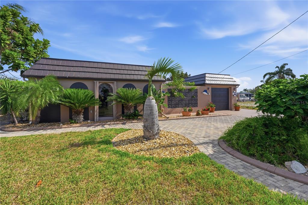 A single-story house with a paved driveway, palm trees, and a dark shingled roof — 12821 4TH ISLE, HUDSON, FL