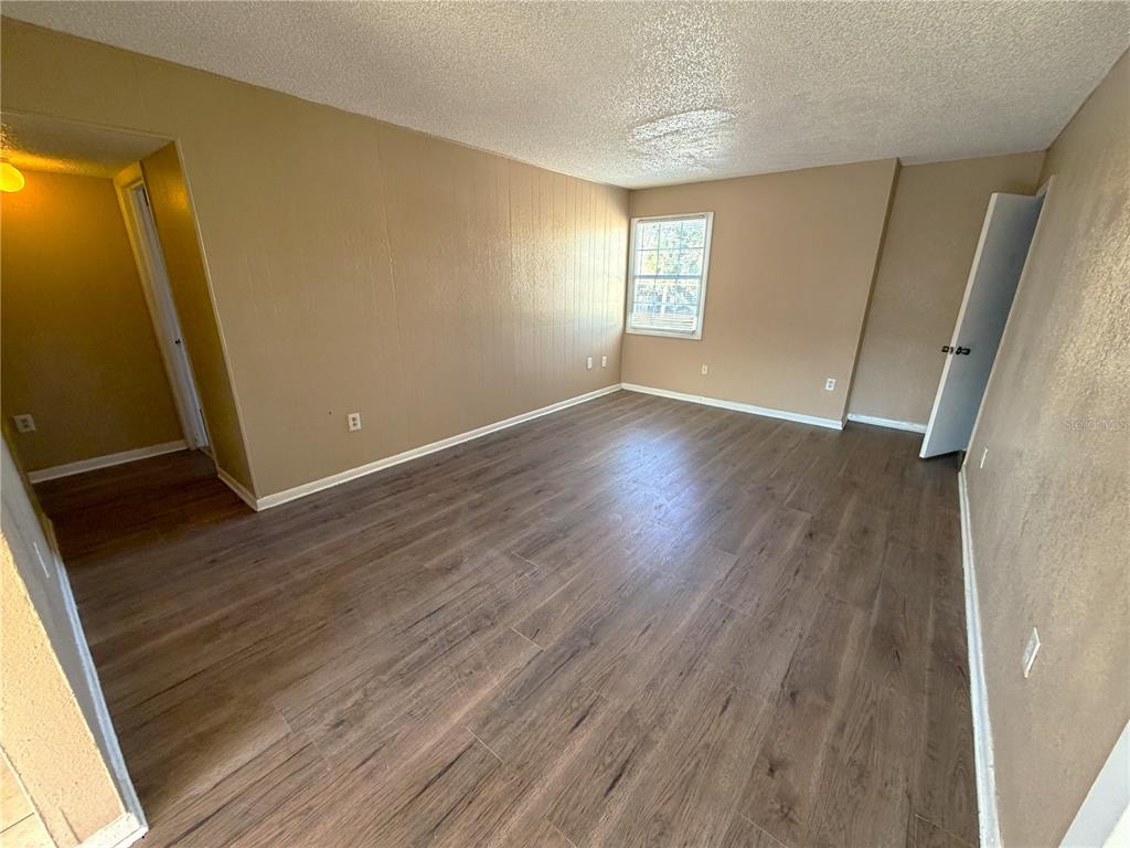 An empty room with tan walls, wood-look flooring, and a single window — 2785 L B MCLEOD ROAD UNIT 2785D, ORLANDO, FL