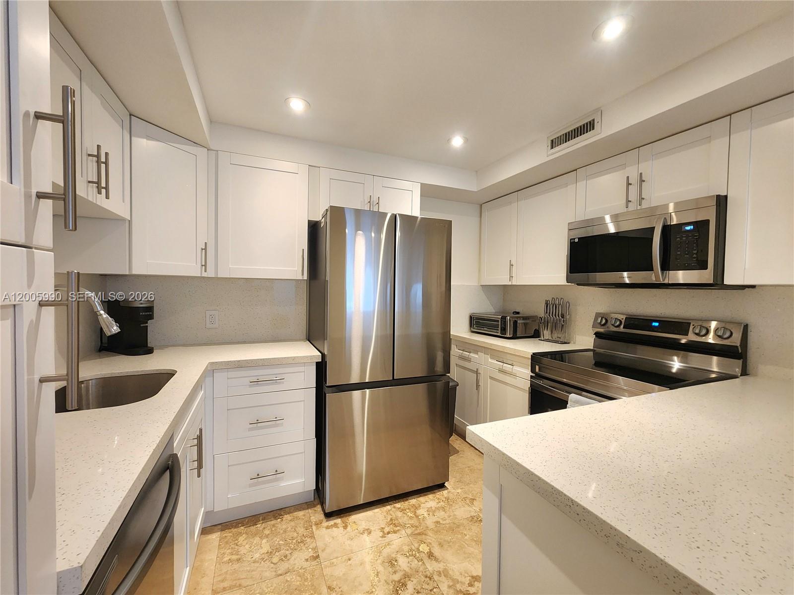 A kitchen features white cabinets, stainless steel appliances, and light-colored quartz countertops — 3505 S Ocean Dr # 209, Hollywood FL 33019, HOLLYWOOD, FL