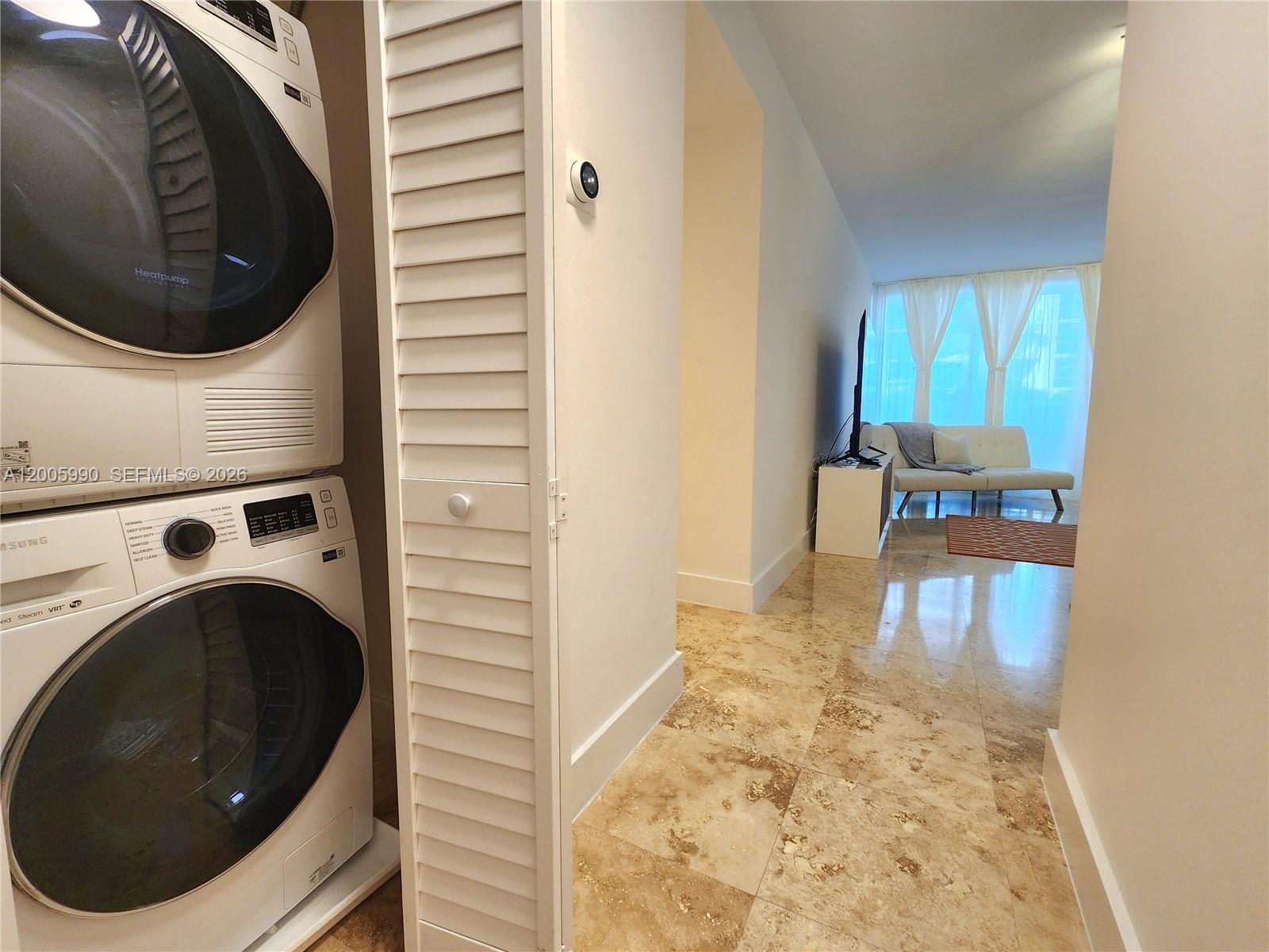 A stacked washer and dryer unit sits beside a hallway leading to a living area — 3505 S Ocean Dr # 209, Hollywood FL 33019, HOLLYWOOD, FL