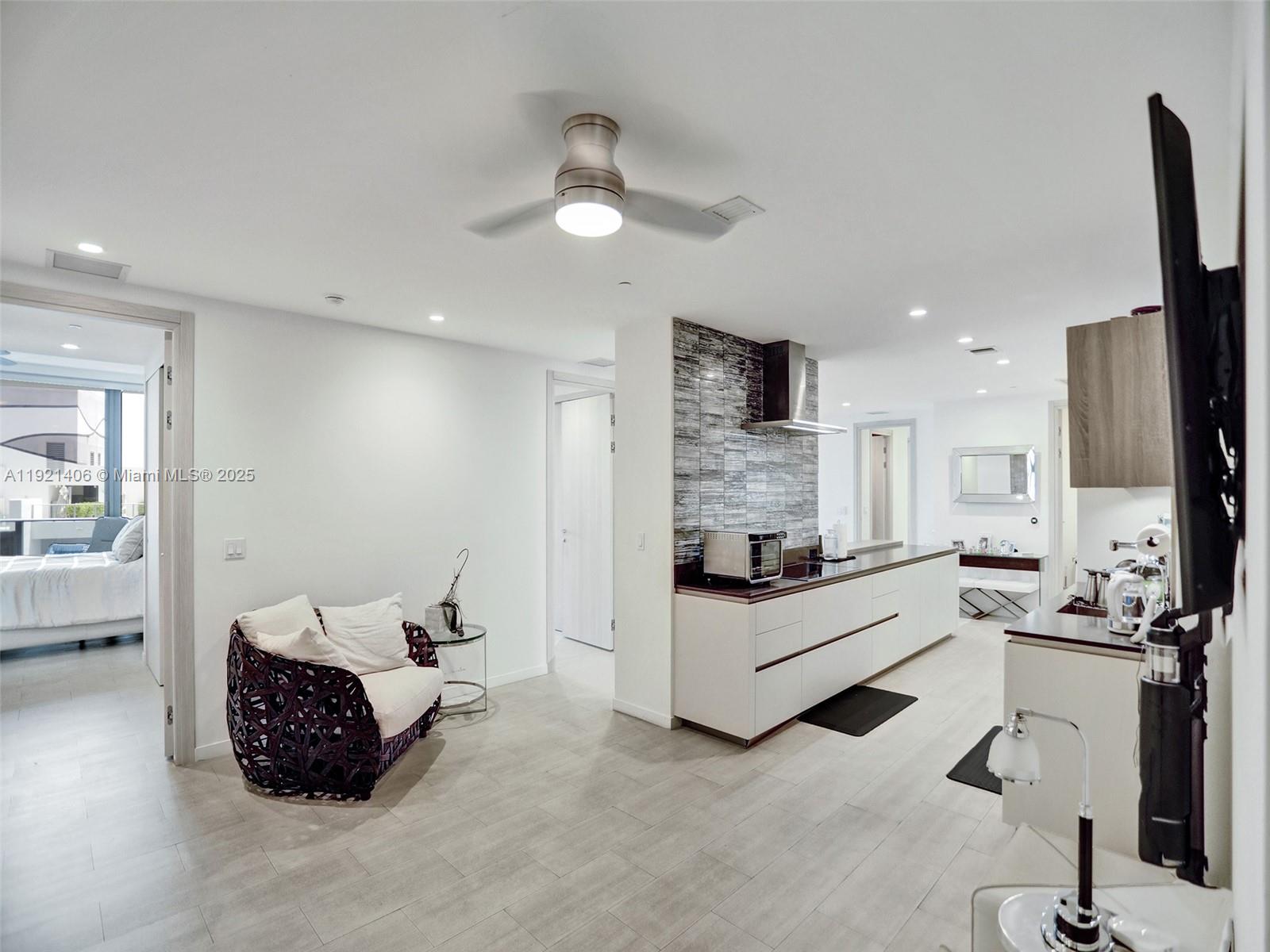 A modern open-concept kitchen and living area features white cabinetry, tile flooring, and a ceiling fan — 1000 Brickell Plz, Miami FL 33131, MIAMI, FL