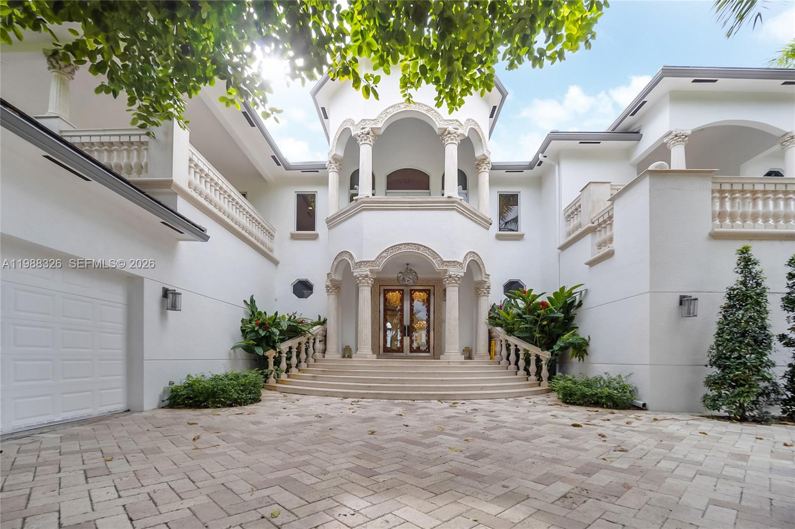 The exterior of a white two-story house features a grand arched entryway with stone columns — 100 Palm Ave, Miami Beach FL 33139, MIAMI BEACH, FL
