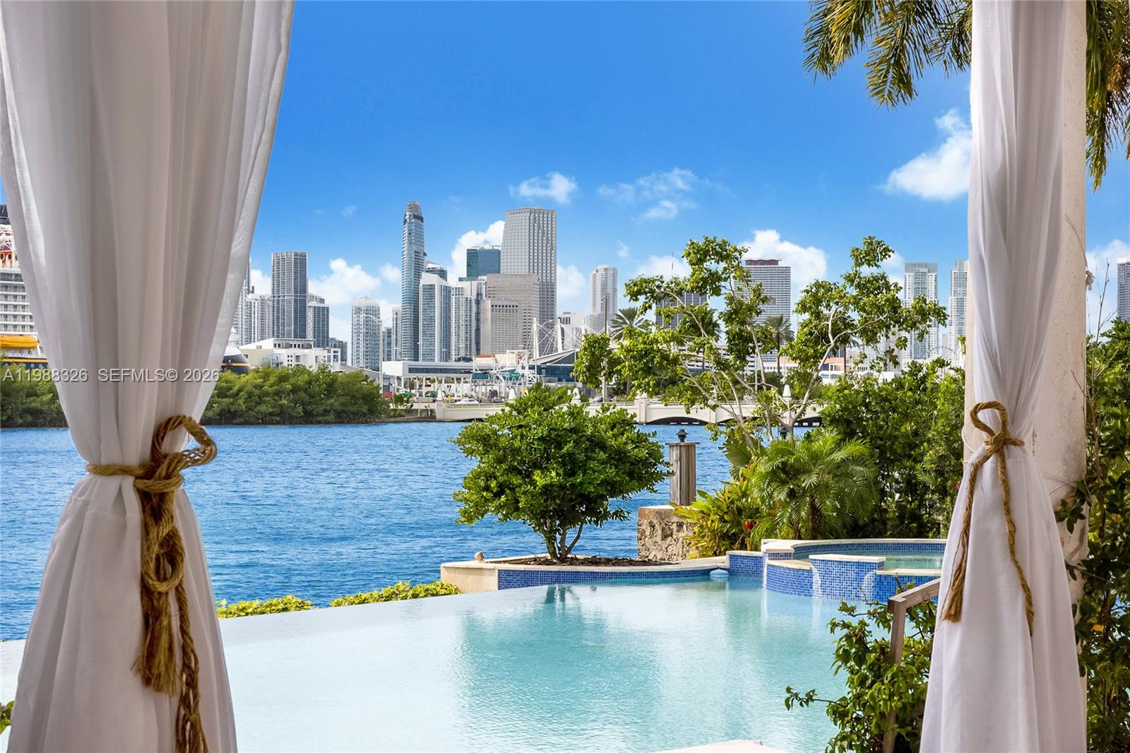 An infinity pool overlooks a bay with a city skyline in the background — 100 Palm Ave, Miami Beach FL 33139, MIAMI BEACH, FL