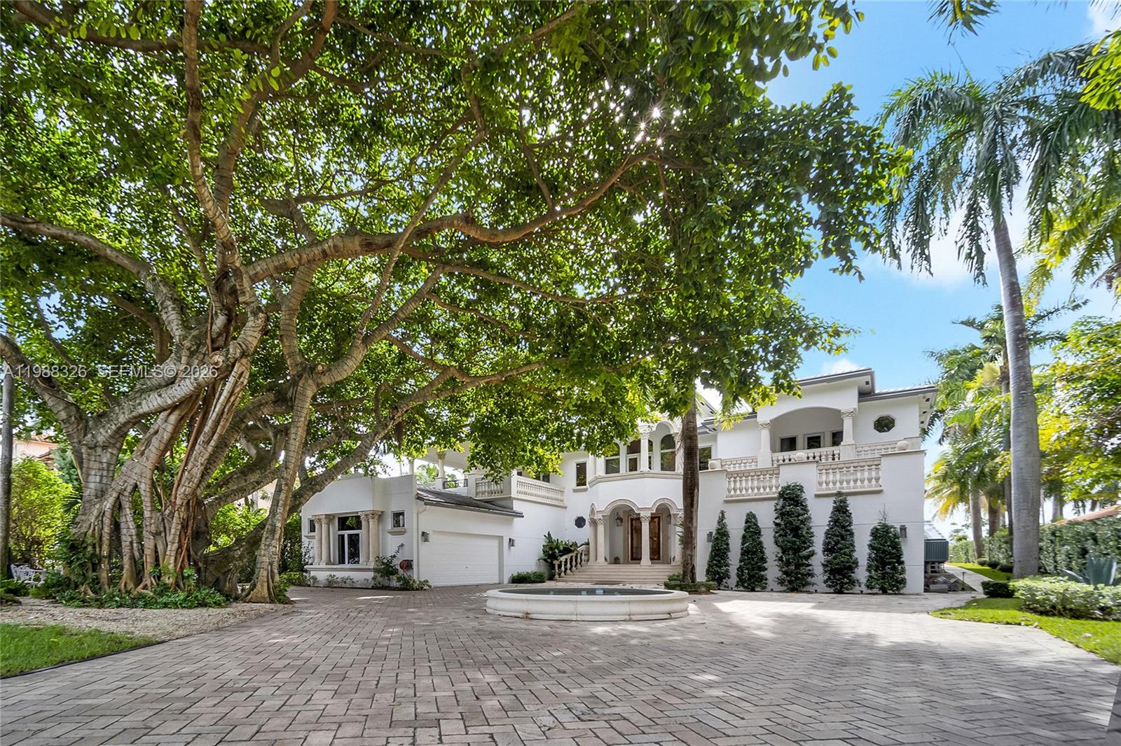 A large white two-story house features a paved driveway, a fountain, and a large tree — 100 Palm Ave, Miami Beach FL 33139, MIAMI BEACH, FL
