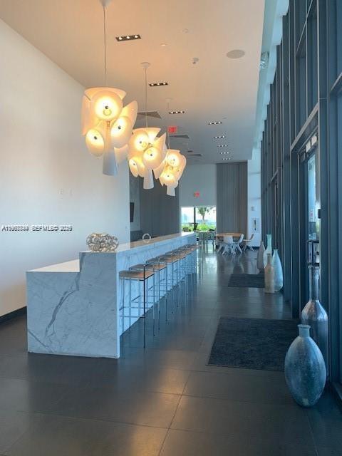 A modern bar area features a marble counter, bar stools, and hanging sculptural pendant lights — 1600 NE 1st Ave # 3319, Miami FL 33132, MIAMI, FL