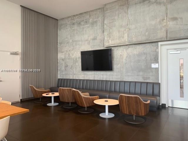 A modern lounge features a long gray bench, wood-accented chairs, and a concrete accent wall — 1600 NE 1st Ave # 3319, Miami FL 33132, MIAMI, FL