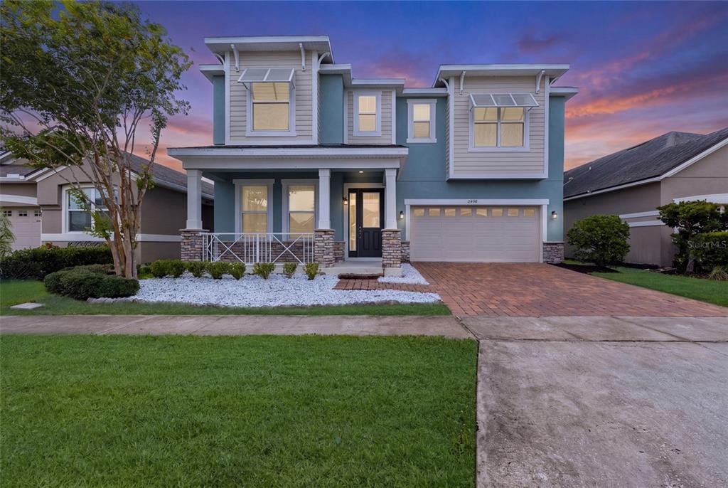 A two-story house with blue siding, a stone-accented porch, and a two-car garage — 2408 CHATEAU LOOP, KISSIMMEE, FL