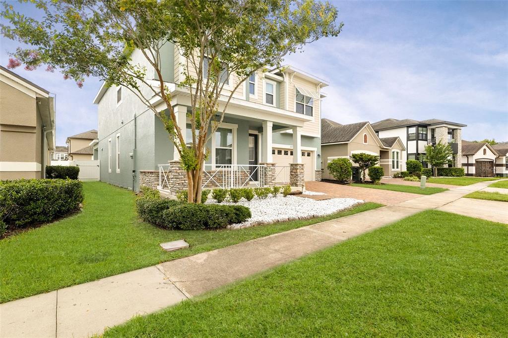 A two-story house with a light green exterior, stone accents, and a front porch — 2408 CHATEAU LOOP, KISSIMMEE, FL