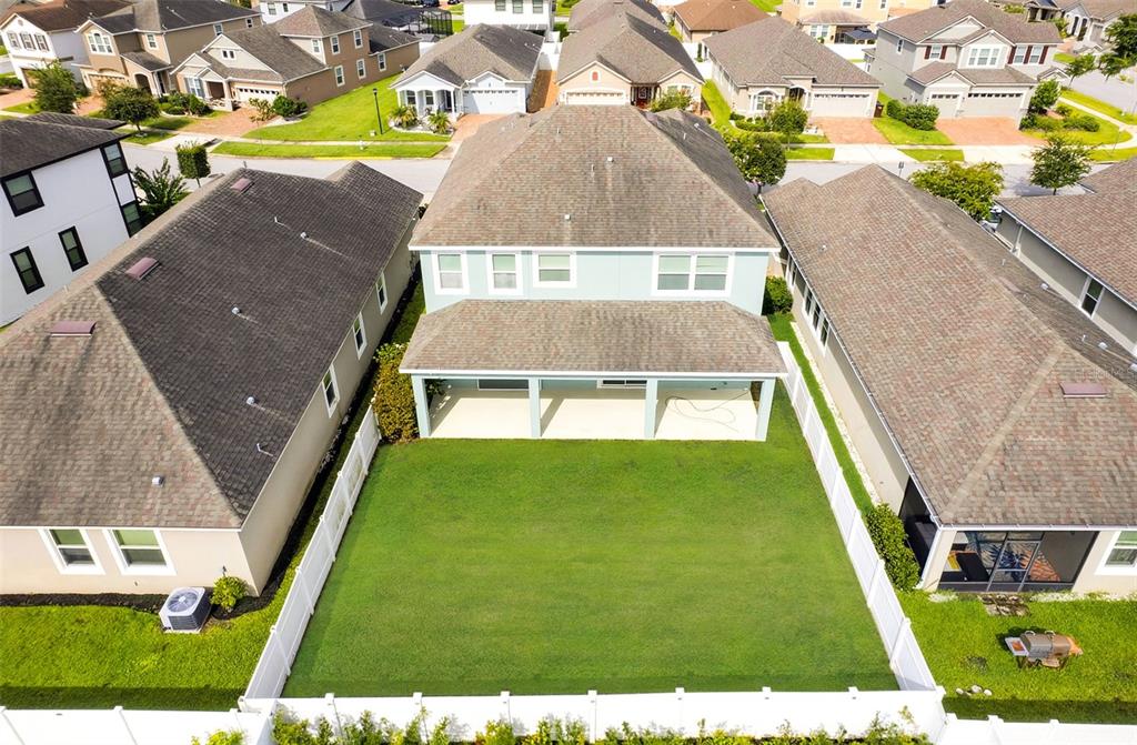 An aerial view shows the backyard and rear exterior of a two-story house with a patio — 2408 CHATEAU LOOP, KISSIMMEE, FL