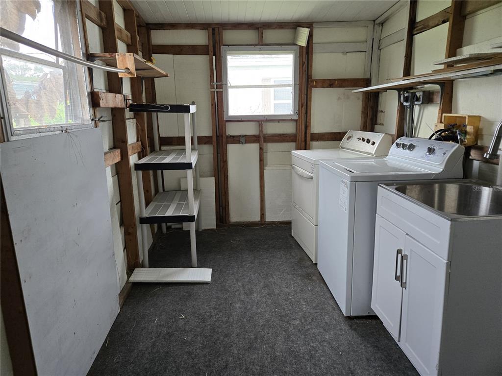 A laundry room with a washer, dryer, utility sink, and exposed wall studs — 3602 N CITRUS CIRCLE UNIT 1529, ZELLWOOD, FL