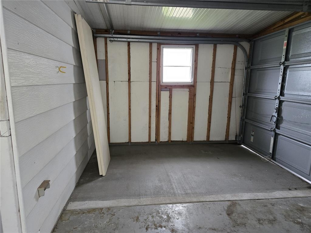 An unfinished garage interior features exposed wall studs, foam insulation panels, and a small window — 3602 N CITRUS CIRCLE UNIT 1529, ZELLWOOD, FL