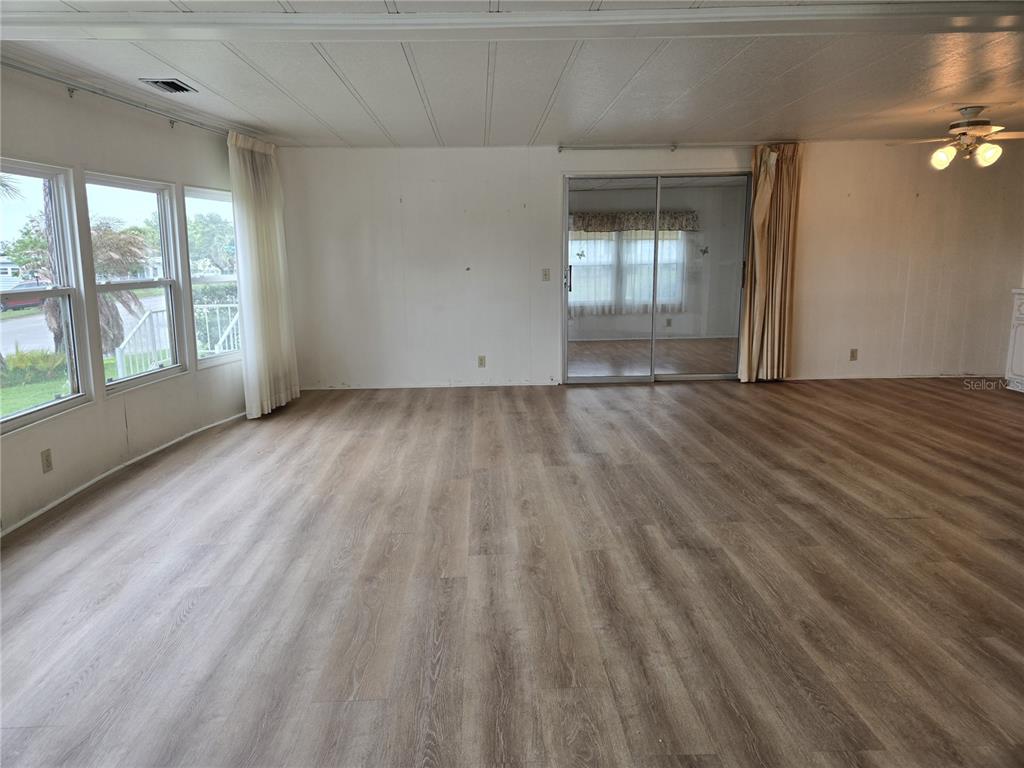 A spacious living room features wood-look flooring, large windows, and sliding glass doors — 3602 N CITRUS CIRCLE UNIT 1529, ZELLWOOD, FL