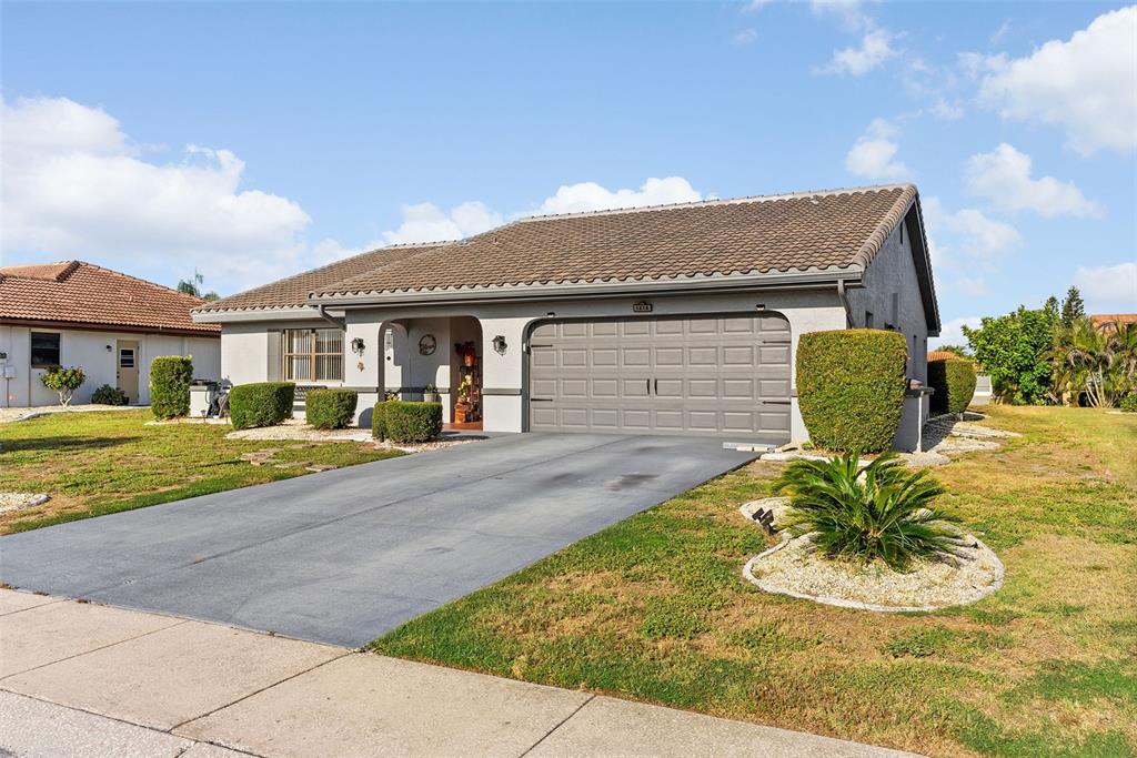 A single-story house with a gray garage door, tile roof, and a concrete driveway — 1816 GRANVILLE LANE, SUN CITY CENTER, FL