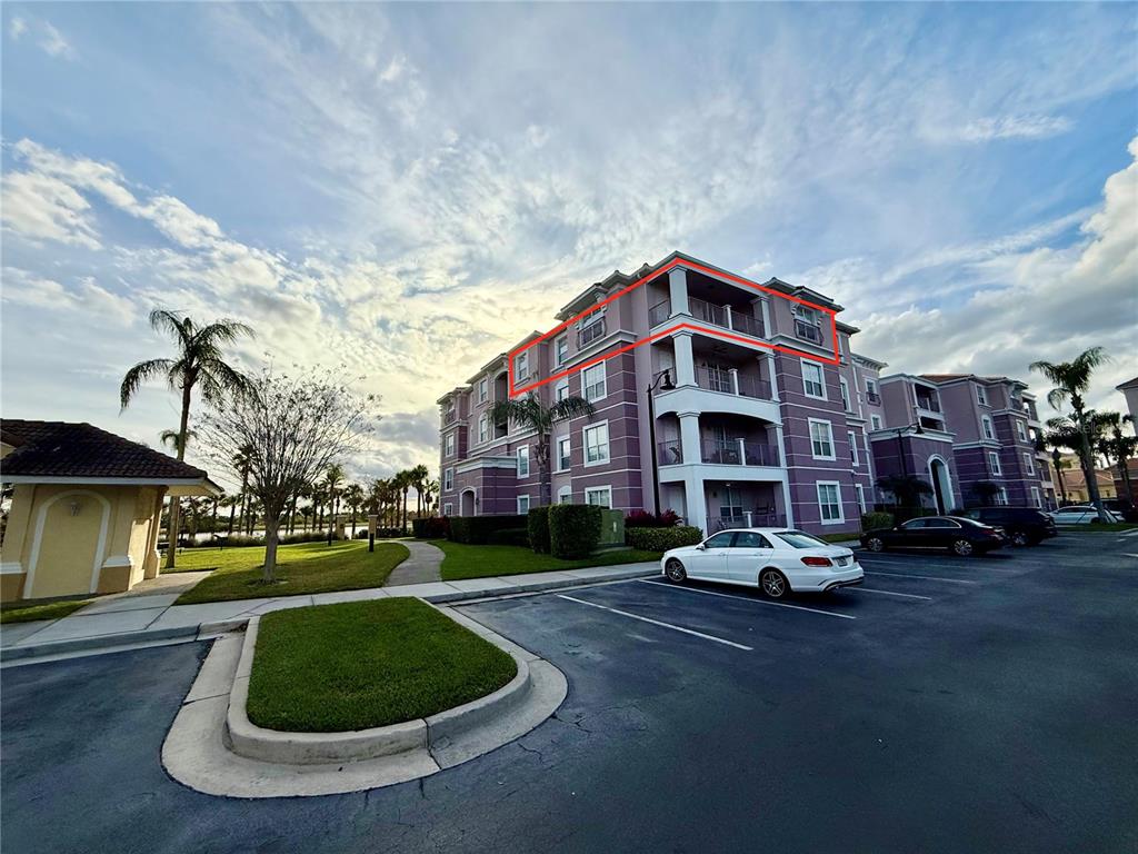 A multi-story apartment building with a highlighted top-floor balcony and exterior parking lot — 4840 CAYVIEW AVENUE UNIT 403, ORLANDO, FL