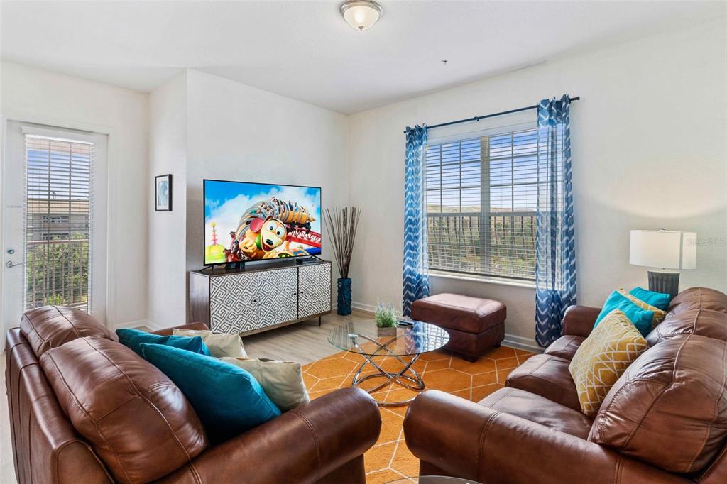 A living room features brown leather sofas, an orange rug, and a television on a console — 4840 CAYVIEW AVENUE UNIT 403, ORLANDO, FL