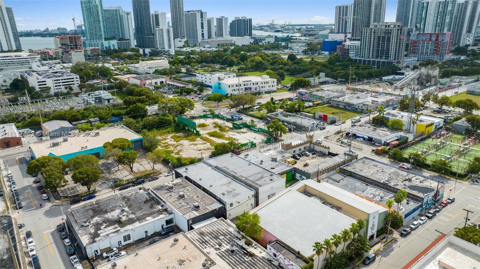 An aerial view shows low-rise commercial buildings, vacant lots, and urban streets near a city skyline — 2010,2014,2020 NW Miami Ct, Miami FL 33127, MIAMI, FL