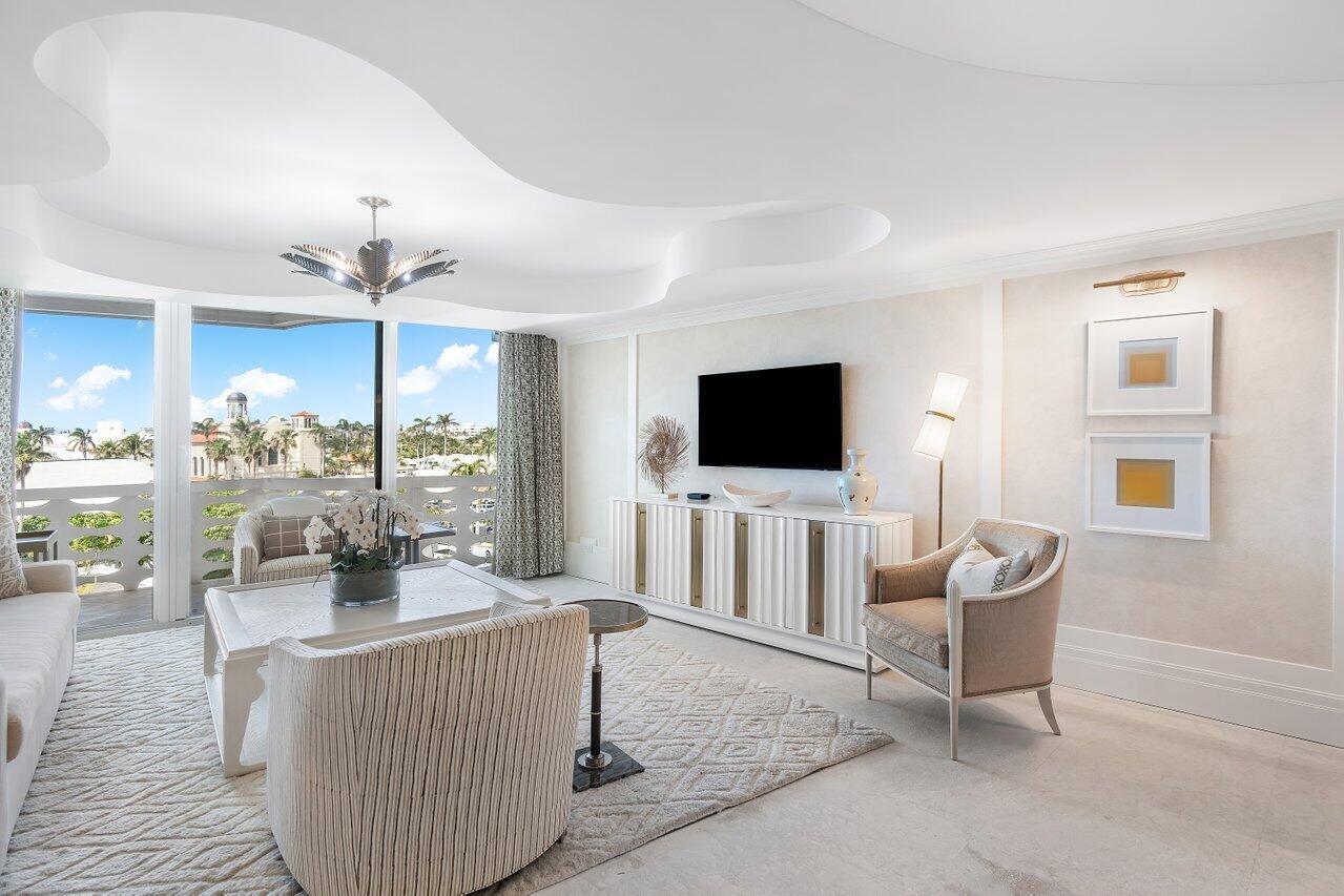 A bright living room features a white media console, patterned area rug, and balcony view — 130 Sunrise Avenue # 616, Palm Beach FL 33480, PALM BEACH, FL