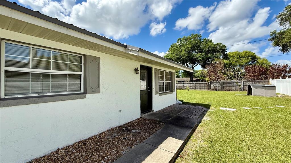 The exterior of a white house features a black door, windows, and a paved walkway — 1516 ALABAMA AVENUE, ST CLOUD, FL