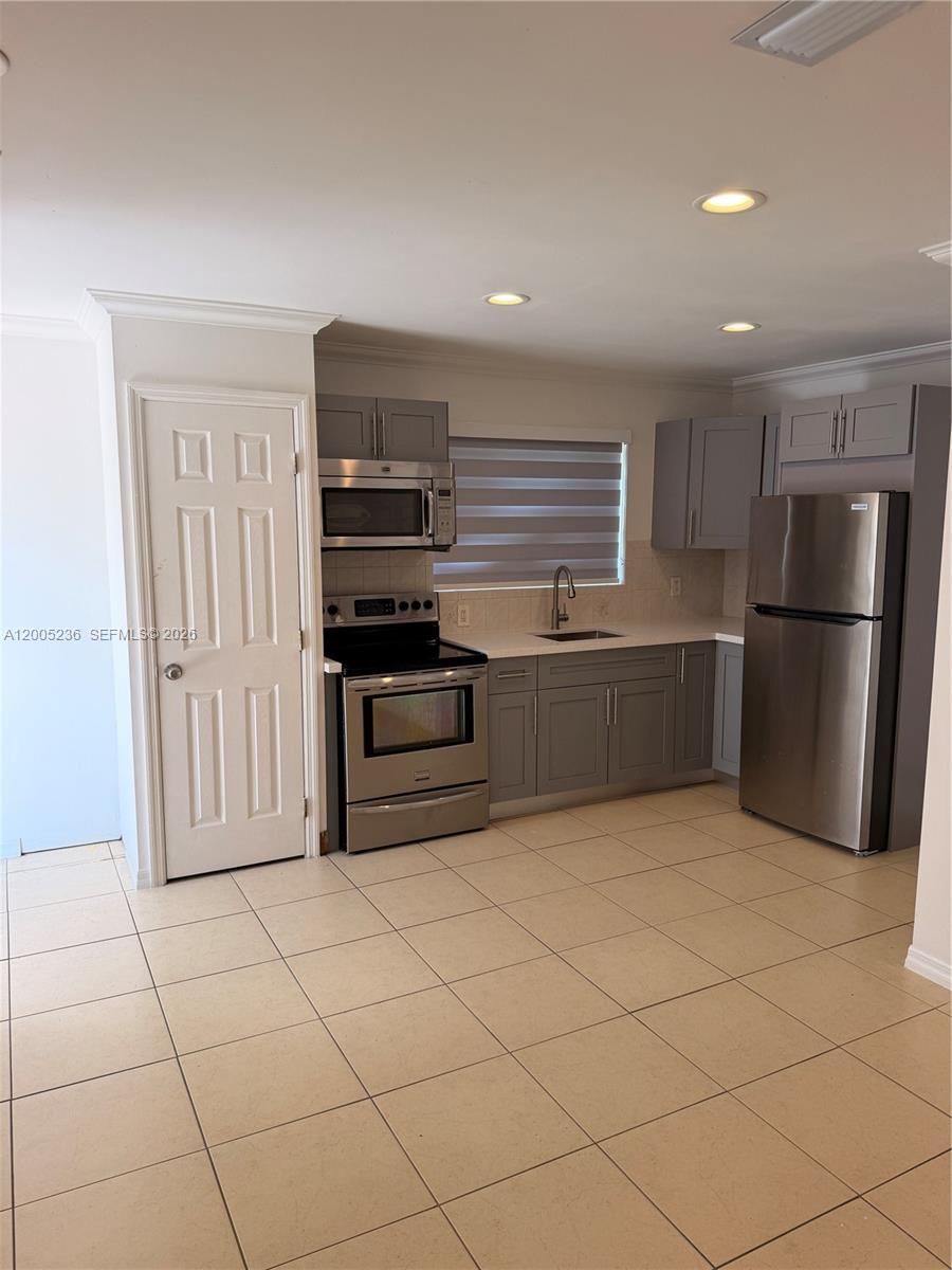A kitchen features gray cabinets, stainless steel appliances, and light-colored tile flooring — 3011 N 74th Ave # B, Hollywood FL 33024, HOLLYWOOD, FL