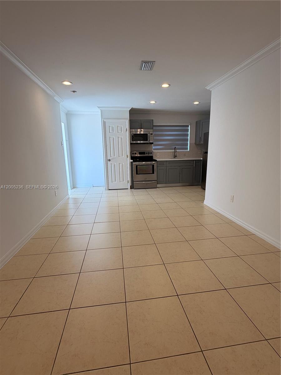 A kitchen with gray cabinets and stainless steel appliances sits at the end of a room — 3011 N 74th Ave # B, Hollywood FL 33024, HOLLYWOOD, FL