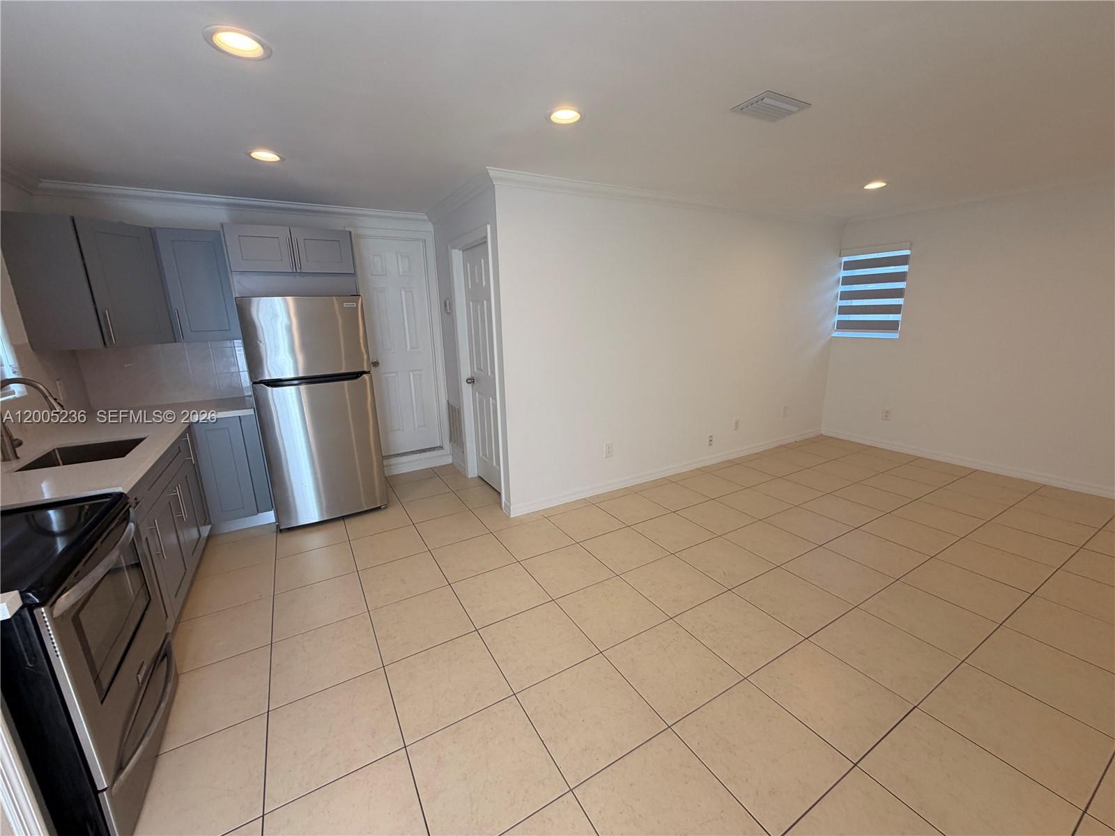 A kitchen with gray cabinets and stainless steel appliances opens into a tiled living area — 3011 N 74th Ave # B, Hollywood FL 33024, HOLLYWOOD, FL