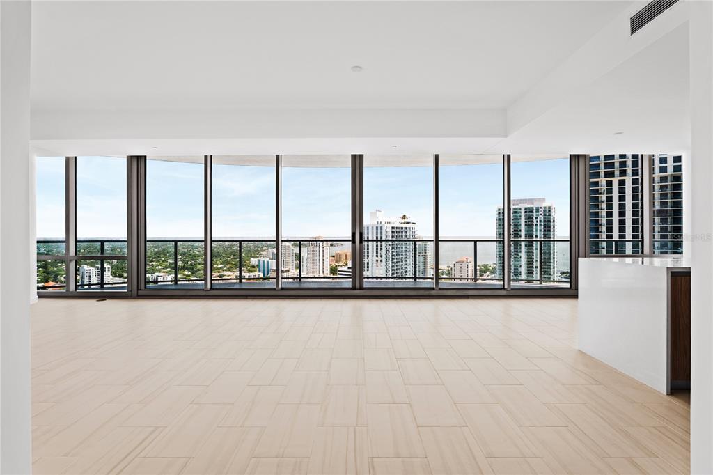 An empty room with light-colored tile floors and floor-to-ceiling windows overlooking a city skyline — 400 CENTRAL AVENUE UNIT 3107, ST PETERSBURG, FL