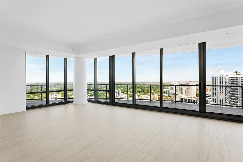 An empty room with light-colored tile flooring and floor-to-ceiling windows overlooking a city skyline — 400 CENTRAL AVENUE UNIT 3107, ST PETERSBURG, FL