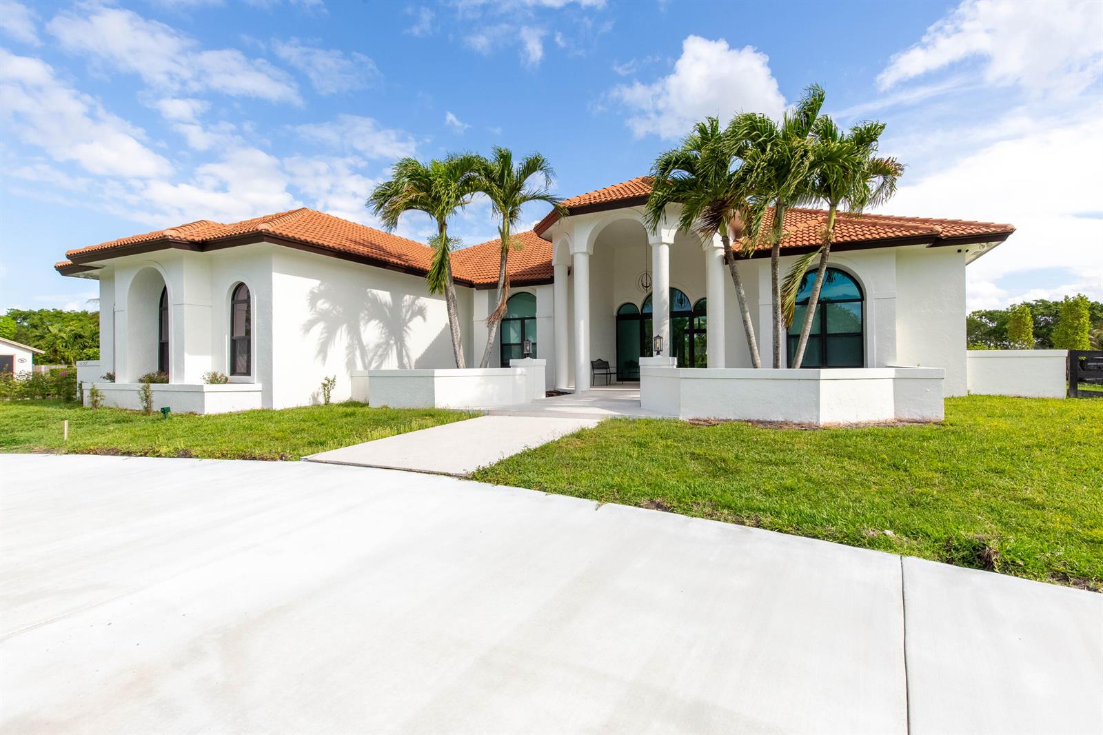 A white, single-story house with a terracotta tile roof and palm trees in the front — 14367 Belmont Trace, Wellington FL 33414, WELLINGTON, FL