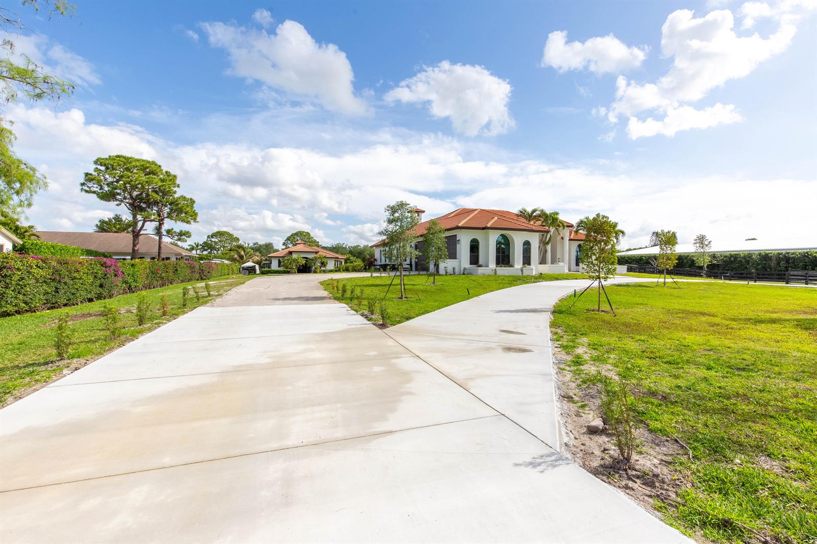 A concrete driveway leads to a white house with a red tile roof — 14367 Belmont Trace, Wellington FL 33414, WELLINGTON, FL