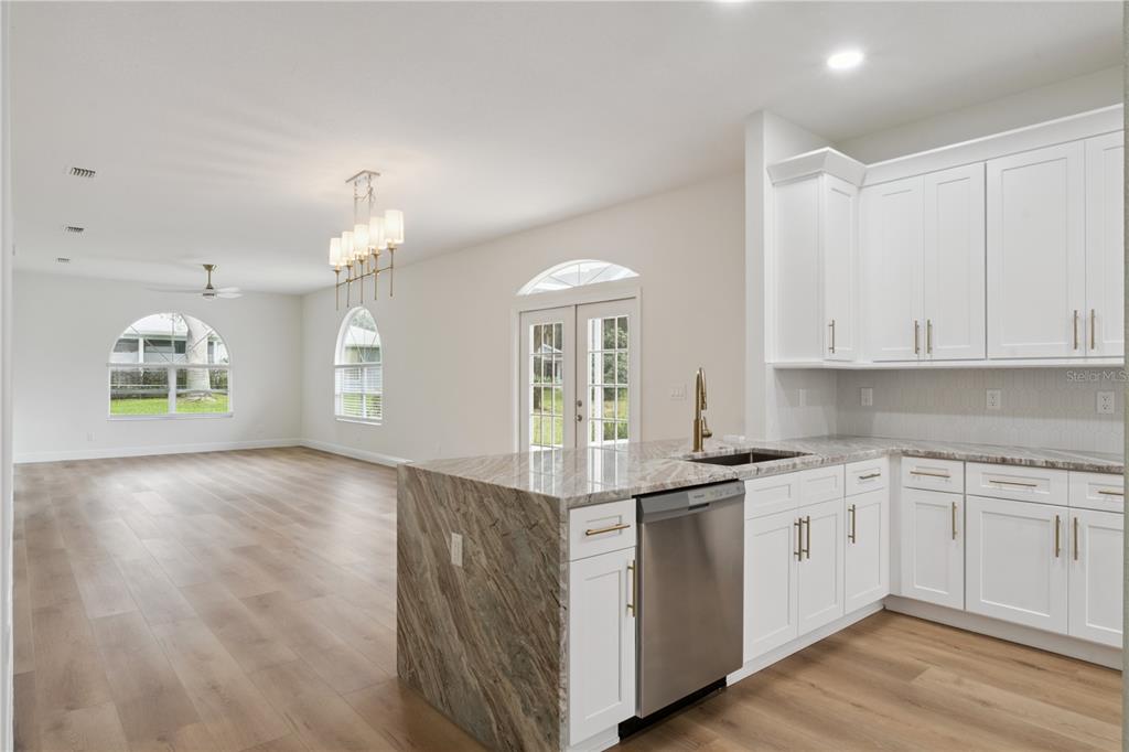 A kitchen with white cabinets and granite countertops opens into a spacious living area — 5619 PRINCE ANDREW COURT, LEESBURG, FL