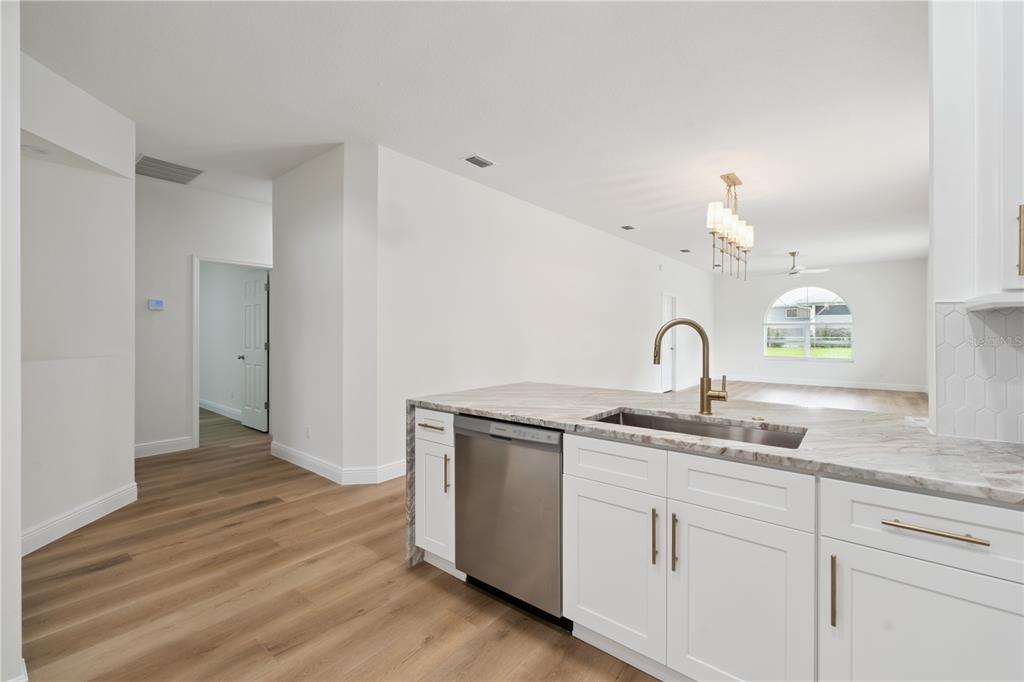 A modern kitchen features white cabinetry, stainless steel appliances, and light-colored stone countertops — 5619 PRINCE ANDREW COURT, LEESBURG, FL