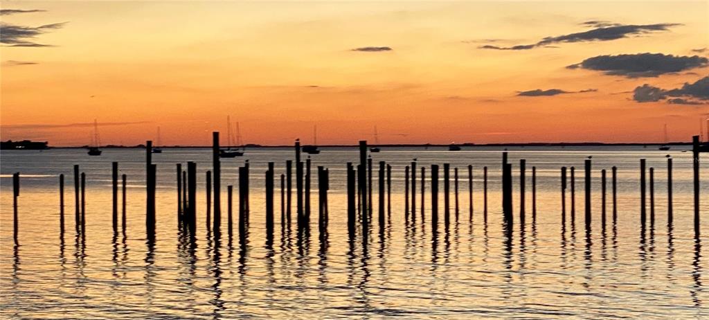 A row of wooden pilings stands in calm water against a vibrant orange sunset — 2083 PORPOISE DRIVE, PUNTA GORDA, FL