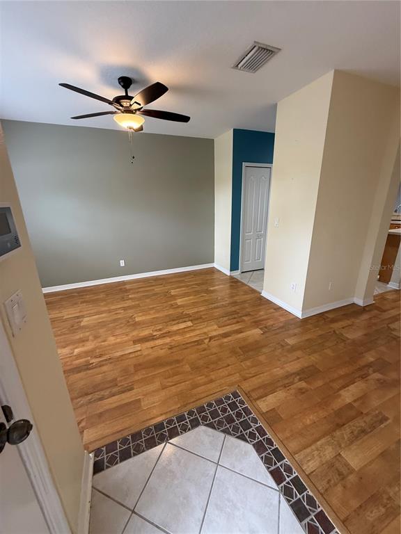 An interior view shows a room with wood flooring, a ceiling fan, and a teal accent wall — 15625 STABLE RUN DRIVE, SPRING HILL, FL
