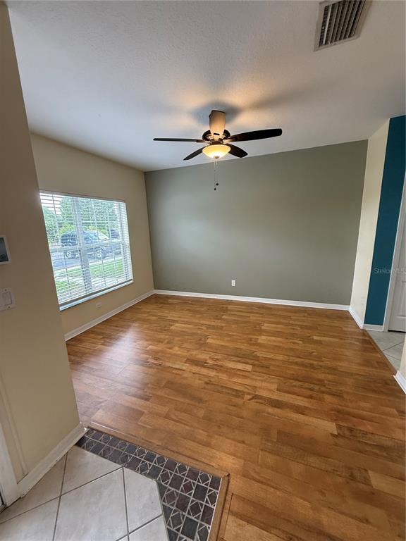 An empty room features wood-look flooring, a ceiling fan, and a large window — 15625 STABLE RUN DRIVE, SPRING HILL, FL