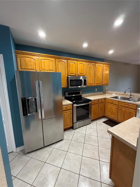 A kitchen features wood cabinets, stainless steel appliances, tile flooring, and blue accent walls — 15625 STABLE RUN DRIVE, SPRING HILL, FL