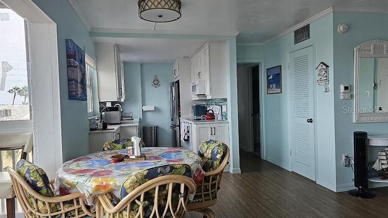 A dining area with a floral-covered table sits adjacent to a light blue kitchen — 1255 TARPON CENTER DRIVE UNIT 304, VENICE, FL